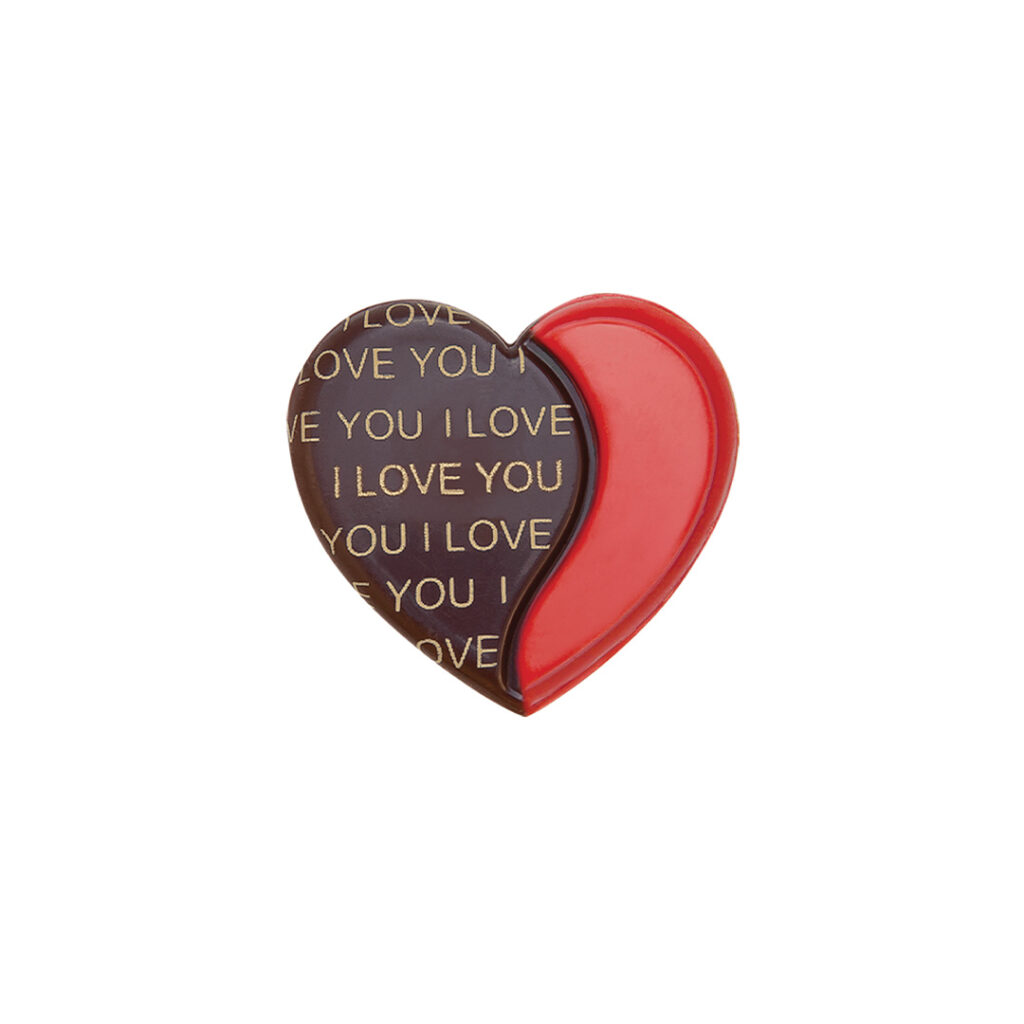 3D heart-shaped chocolate decoration split into two sections: one side is dark chocolate with 'I LOVE YOU' printed repeatedly in gold, and the other is smooth, vivid red chocolate